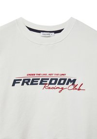 Felpa bianca con la scritta "FREEDOM Racing Club" in testo blu navy e rosso. Collo rotondo e texture morbida. Etichetta del marchio "CALLIOPE."