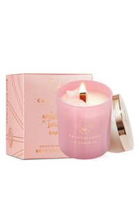 Naturalna świeca sojowa w różowym szklanym pojemniku z drewnianym knotem, ozdobiona kryształami różowego kwarcu, w towarzystwie różowego pudełka z złotymi akcentami.