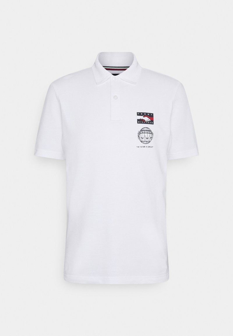 Polo blanc avec col, manches courtes et un motif sur le côté gauche de la poitrine. Il comporte un patch logo et un dessin de globe avec du texte.