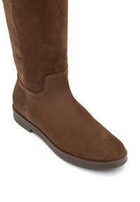 Barna velúr térdfeletti csizma sima felülettel, kerek orral és diszkrét varrási részletekkel. Lapos gumitalp a stabilitás érdekében.