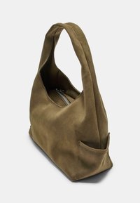 Sac à main en suede vert olive avec une texture douce, un design décontracté et une poignée courte unique. Comprend un compartiment zippé et une poche latérale.