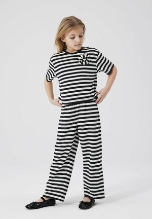 Striped black and white t-shirt and wide-leg pants set with a bow accent on the shirt. The outfit has a relaxed fit and soft texture.