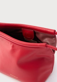 Borsa a mano in pelle rossa con texture liscia e forma arrotondata. Dispone di una tasca interna e di una chiusura a scatto per un accesso sicuro.