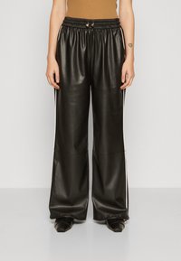 Pantalones anchos de imitación de cuero negro con cinturilla elástica, que presentan rayas laterales blancas. Textura suave y detalles de diseño minimalistas.