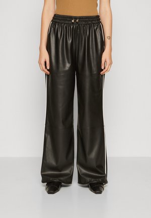 Pantaloni a gamba larga in finta pelle nera con vita elasticizzata, caratterizzati da strisce laterali bianche. Texture liscia e dettagli di design minimalisti.
