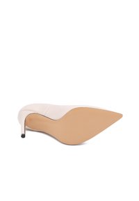 Scarpa con tacco alto beige, dalla punta affusolata e dal design elegante. La suola è liscia, di un colore tan chiaro, con un tacco sottile nero.