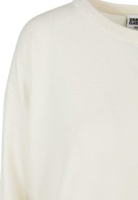Hvit strikket genser med rund hals og løs passform. Stoffet har en myk tekstur, ideell for lag-på-lag eller avslappet bruk.
