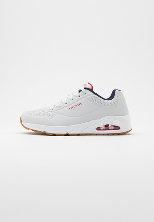 Weißer Skechers Sneaker mit Gummisohle, rotem Logo, navyfarbenem Innenfutter und sichtbarem Luftpolster in der Ferse, von der Seite auf weißem Hintergrund gezeigt.