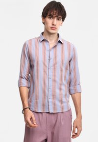 Camisa de botones a rayas en azul claro y rosa, tela texturada, mangas largas remangadas, botones en el frente, combinada con pantalones rosas claros a juego.
