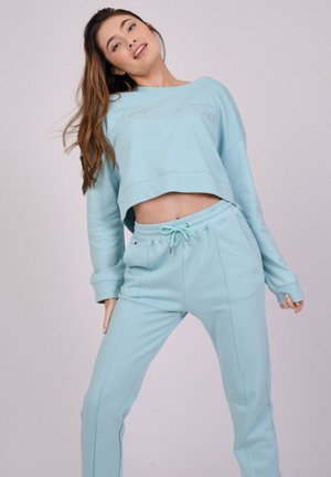 Lichtblauwe cropped sweatshirt met geborduurde tekst. Gecombineerd met bijpassende sweatpants met een trekkoord in de taille en zijzakken.