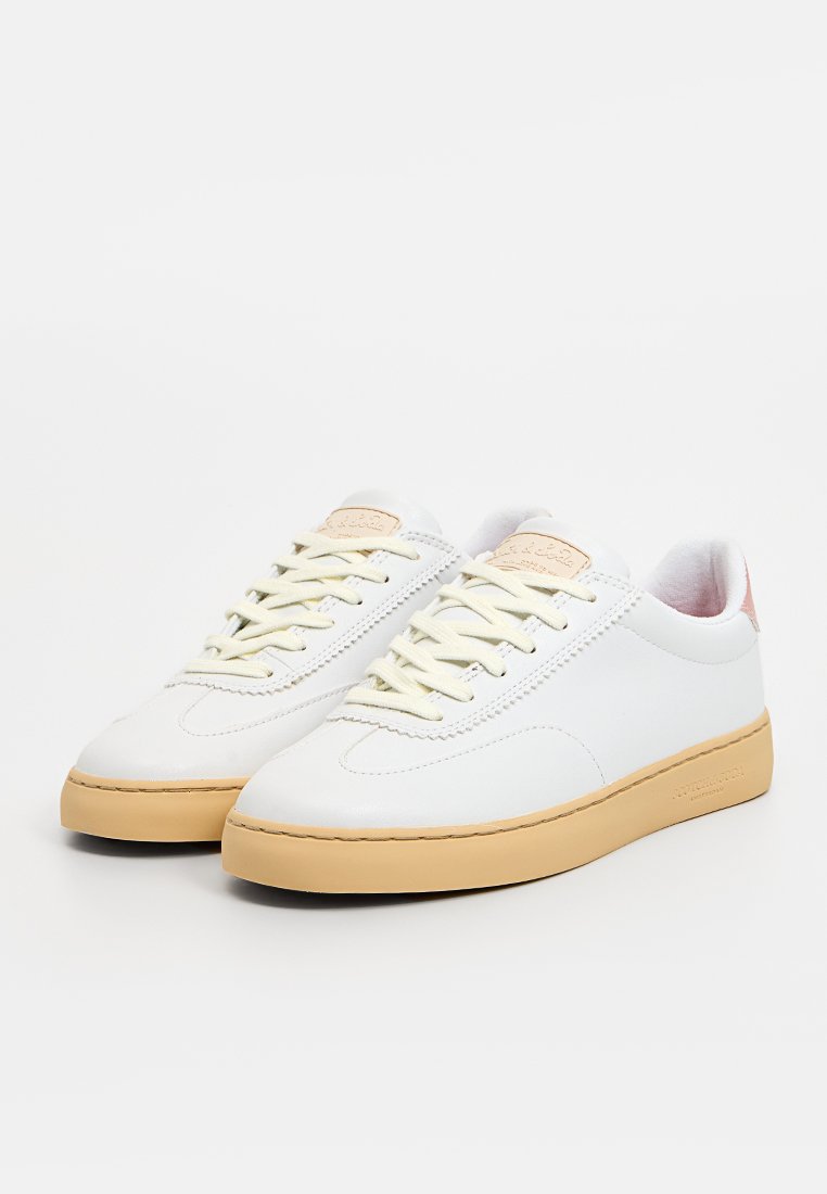 Baskets en cuir blanc avec une finition texturée, semelles en caoutchouc beige et accents rose pâle au niveau du talon. Elles présentent des lacets et des détails cousus.