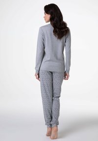 Maglia grigia a maniche lunghe con scollatura rotonda, abbinata a pantaloni grigi chiari con un sottile motivo a stelle. Tessuto morbido, vestibilità comoda.