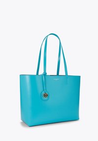 Turkusowa torba na ramię wykonana z gładkiej skóry, z dwoma uchwytami, z okrągłym złotym emblematem i detalem logo z jednej strony.