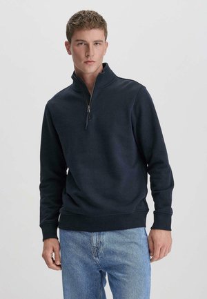 Marineblauwe ritsvest met staande kraag, ribgebreide manchetten en zoom. Zachte katoenmixstof met een minimalistisch ontwerp.