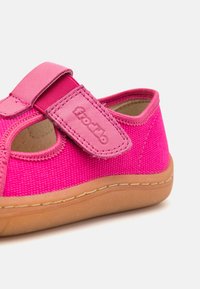 Ροζ υφασμάτινο παπούτσι με ιμάντα αυτοκόλλητης περίφραξης, καφέ καουτσούκ σόλα και κομμένα πλαϊνά για αναπνοή. Υφή στην άνω πλευρά με λεπτομέρεια λογότυπου.