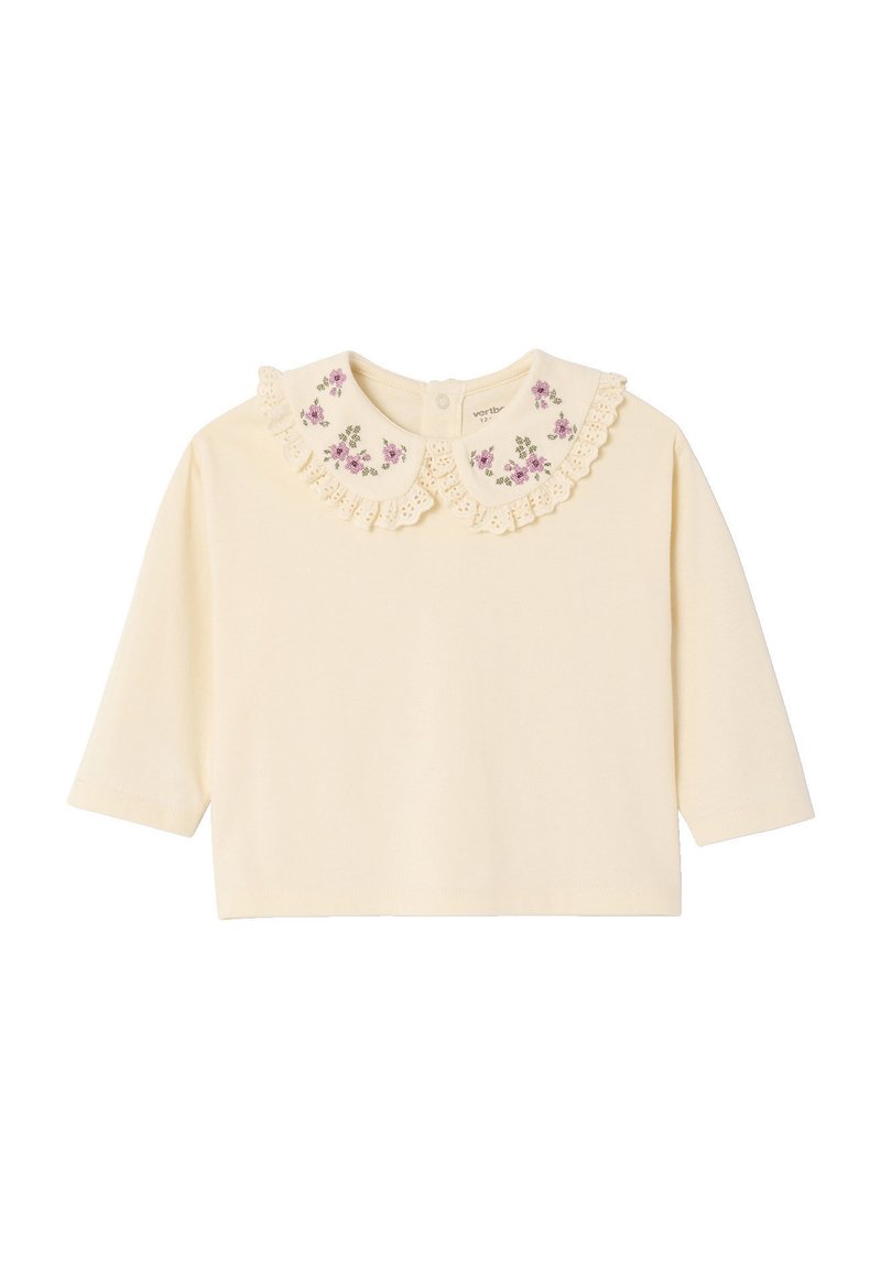 Cream long-sleeve top featuring a lace-trimmed, embroidered collar with floral patterns. Soft fabric and rounded hem for a relaxed fit.