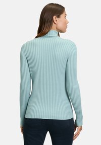 Light blue ribbed turtleneck sweater with long sleeves and a fitted silhouette, featuring fine vertical lines for texture.