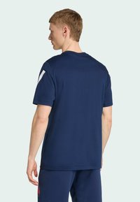 Mörkblå t-shirt med korta ärmar, rund halsringning och vita accenter på axlarna; slät textur och enkelt mönster.