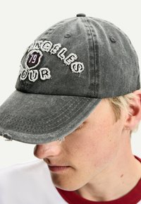 Căciulă din denim gri cu text brodat "Angeles Tour 79", având oxton vârf ușor uzat și curea ajustabilă la spate.