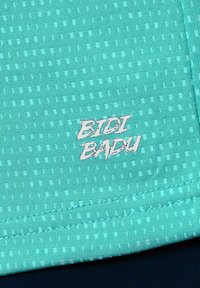 Tejido atlético turquesa con un patrón de cuadrícula texturizado; presenta el logotipo blanco "BIDI BADU" exhibido en la parte inferior.