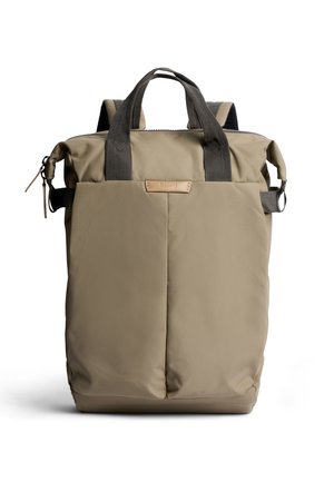 Zaino rettangolare beige con fronte imbottito, manici grigio scuro, cerniera superiore e fibbie laterali su sfondo bianco.