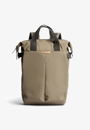 Zaino rettangolare beige con fronte imbottito, manici grigio scuro, cerniera superiore e fibbie laterali su sfondo bianco.