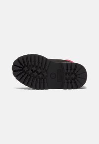 Suela de goma negra con un patrón de tracción resistente. Presenta un logo de Timberland y acentos en rosa a lo largo del borde superior. Diseño duradero.