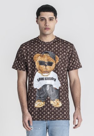 Brown graphic t-shirt featuring a teddy bear in sunglasses and a white shirt, surrounded by a repeating logo pattern.