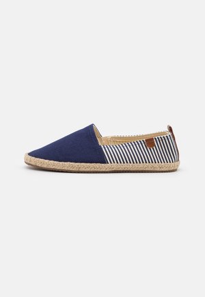 Espadrille à enfiler avec devant bleu marine, arrière en tissu rayé bleu marine et blanc, semelle en jute tressée et languette en cuir marron au talon.