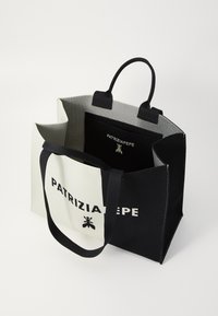 Torba na ramię z płótna w czerni i bieli o strukturalnym designie, z wyraźnie widocznym logo "PATRIZIA PEPE". Wytrzymałe uchwyty.