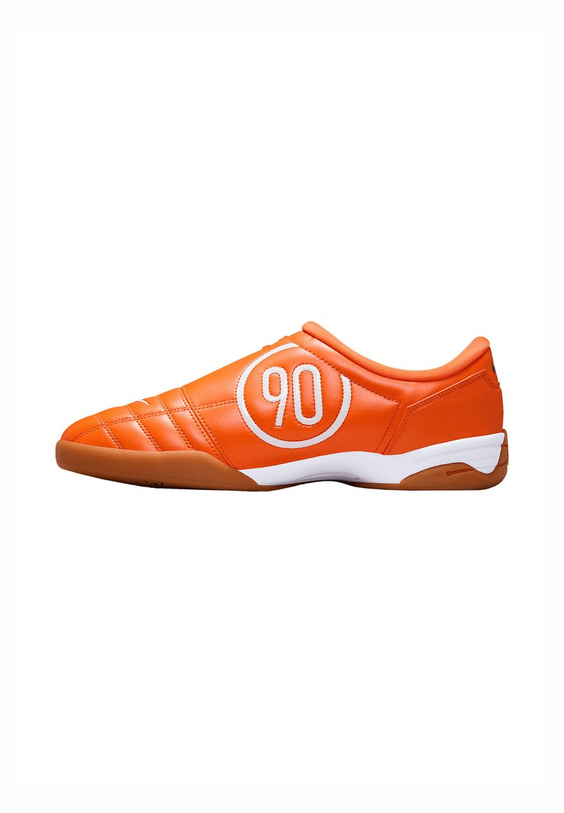 Chaussure de sport orange avec une tige en cuir texturé, arborant un logo circulaire blanc avec le "90" et une semelle en caoutchouc marron.