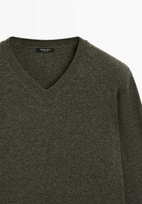Pull en laine vert foncé à col en V avec manches longues, étiqueté Massimo Dutti, fabriqué en Chine, présenté sur un fond blanc.