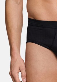 Slip da bagno neri realizzati in tessuto elastico liscio, con un design aderente caratterizzato da sottili righe verticali e una vita morbida.