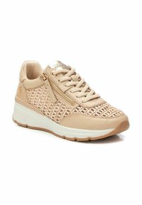 Zapatillas beige con textura tejida en los laterales, cuero suave y detalle de cremallera dorada. Suela ligera con acentos en blanco y marrón claro.