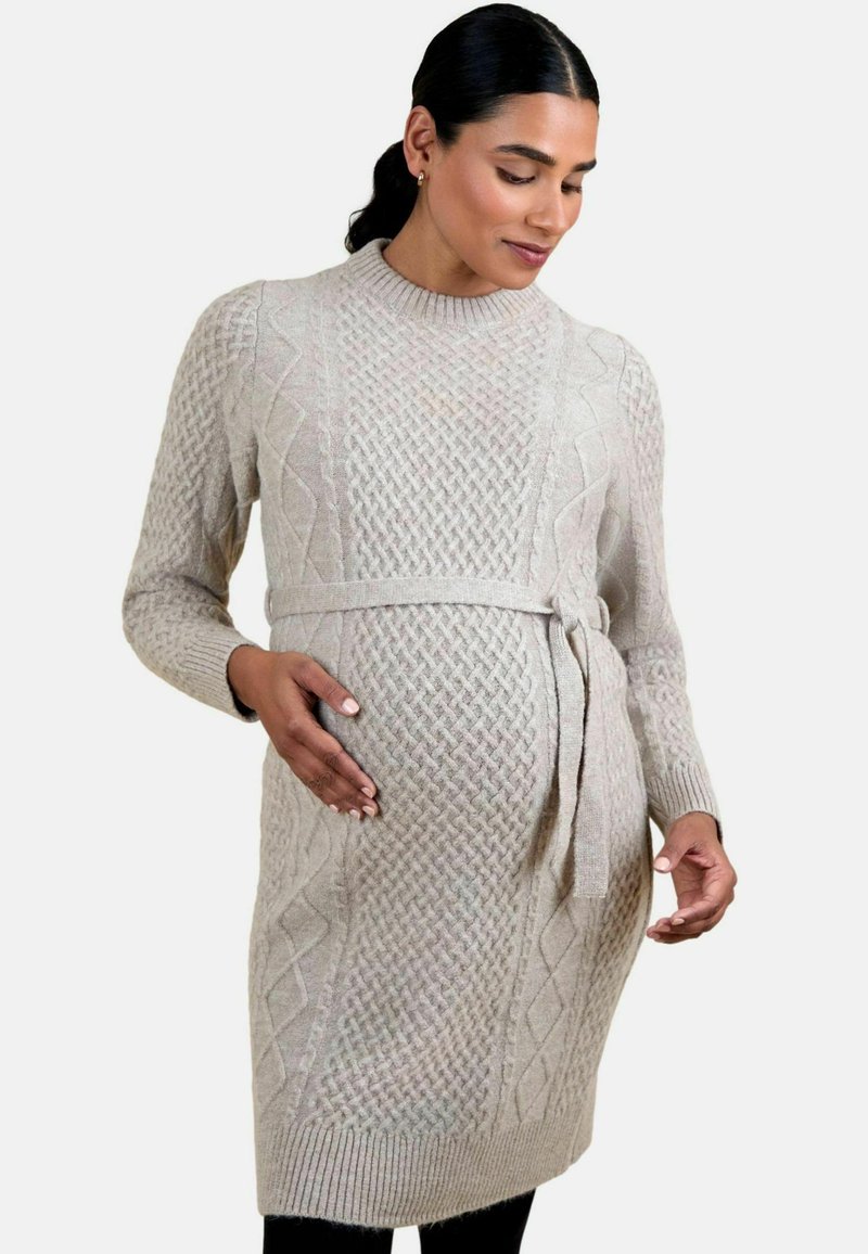 Hellgraues gestricktes Umstandskleid mit strukturiertem Muster, langen Ärmeln und einem abnehmbaren Knotenbund in der Taille, kombiniert mit schwarzen Leggings.