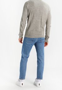 Harmaa pitkähihainen villapaita, siniset farkut ja valkoiset lenkkarit. Villapaidassa on ribbineulos, farkut ovat suorahkot taka-taskuilla.