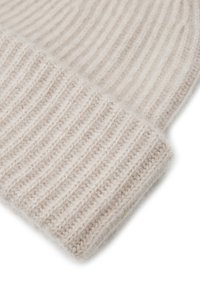 Beige gebreide beanie met verticale ribbels en een zachte textuur; heeft een omgeslagen rand en een gezellige, warme uitstraling.
