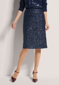 Navy paillettenrok met een aansluitend ontwerp, knielengte, textuur oppervlak, gecombineerd met puntige, glanzende bordeauxrode hakken.