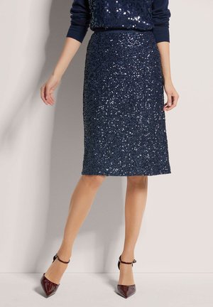 Marineblauer Paillettenrock mit taillierter Passform, knielang, strukturiert, kombiniert mit spitz zulaufenden, glänzenden burgunderfarbenen High Heels.