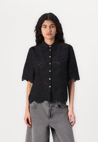 Svart knappopp bluse med korte ermer, med broderte øyelet detaljer, bølgete kanter og en avslappet passform.