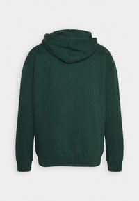 Donkergroen hoodie met een ruime capuchon, lange mouwen en geribde manchetten en zoom. Gemaakt van een zachte, gestructureerde stof. Eenvoudig ontwerp.