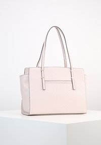 Light pink leather tote bag with subtle embossed pattern, two long handles, and a slim front pocket, displayed on a white surface.