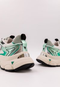 Sneaker chunky bianche, argentate e verde menta. Presentano una tomaia in mesh, dettagli riflettenti e una spessa suola beige con trazione nera.