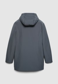 Giacca impermeabile grigia con cappuccio, maniche lunghe e silhouette dritta, caratterizzata da cuciture ridotte al minimo e assenza di chiusure visibili.