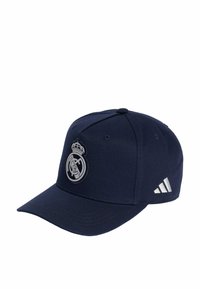Casquette de baseball marine en tissu avec une visière incurvée. Présente un logo Real Madrid argenté et trois rayures blanches sur le côté.