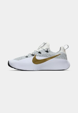 Baskets de course blanches et grises avec un dessus texturé, grand swoosh Nike doré sur le côté, œillets noirs, semelle blanche et languette au talon.