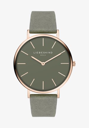 Rund ur med en mørkegrøn urskive og rosaguld detaljer. Har et blødt, tekstureret, lys grønt rem. Minimalistiske timemarkører.