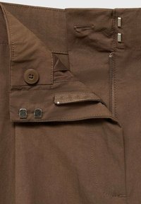 Brown trousers with a button and zipper closure, featuring metal hardware and a textured waistband, displaying a smooth, uniform fabric.