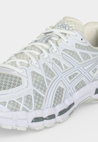 Λευκό και γκρι παπούτσι τρεξίματος ASICS με επάνω μέρος από πλέγμα, κλείσιμο με κορδόνια και μαξιλαρωμένη σόλα με λογότυπα και σχεδιασμό FluidFit.
