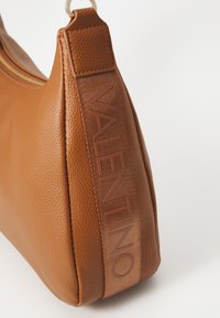 Bolso de cuero marrón con un acabado texturizado, que presenta un destacado logo de VALENTINO en relieve tonal en el lateral y un cierre superior con cremallera.